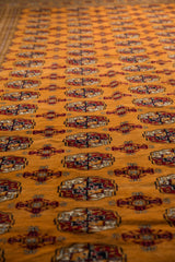 A low-angle perspective showing the plush, lustrous pile and repeating gul medallions of a Bokhara carpet.