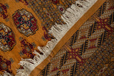 Corner detail of a vintage Bokhara carpet, highlighting its original selvage and plush tangerine pile.