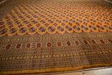 A long perspective view of the repeating gul medallions on a vintage Pakistani carpet.