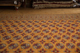 A low angle view across the lustrous tangerine orange pile of a vintage Pakistani Bokhara carpet.