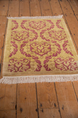 Embossed pale raspberry Damask floral motif with saffron field and ivory fringe.
