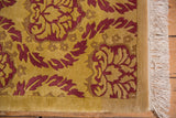 Indian Damask rug corner showing embossed raspberry red pattern and ivory fringe.