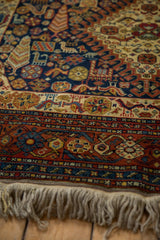 Shiraz design carpet detail: navy field, animals, Cyprus trees, rust border, and fringe.