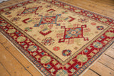 Geometric sapphire blue and cherry red serrated florals on ivory field with detailed red border of the Kazak rug.