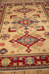 Ivory hand-knotted Kazak design rug detail with red, blue, and green serrated floral motifs.