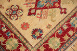 Corner of a new Pakistani Kazak rug, with ivory field, cherry red border, and sapphire blue geometric florals.