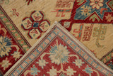 Pakistani Kazak rug folded corner, intact selvage, ivory, red, blue serrated floral patterns.
