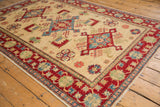New Pakistani Kazak design rug with intact selvage, cherry red border, and blue floral motifs.