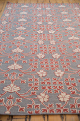Low angle highlighting the raised red and ivory floral pattern on a silver flatweave carpet.