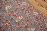 A close-up of the mixed raised pile and flatweave texture with red and ivory floral motifs.