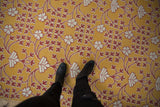 Mixed-texture weave of a Samarkand carpet with raised ivory florals on a saffron yellow ground.