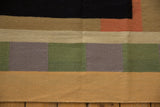 Hand woven contemporary Kilim carpet detail, geometric black, sand, green, and blush sections.
