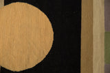 Contemporary Kilim carpet detail: abstract beige circle, black field, and striped border.