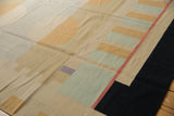 Abstract geometric patterns of pale green, reddish, and black on a contemporary Kilim rug.
