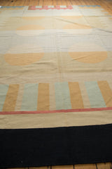 Contemporary hand woven Kilim featuring a black border, raspberry line, and beige and blue patterns.
