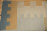 Hand woven contemporary kilim with interlocking stepped pattern in blue-grey, sand, and beige.