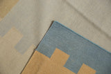 Corner detail of contemporary kilim rug featuring interlocked beige, tan, and powder blue shapes.