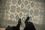 A Kazak rug's full pile and stepped geometric medallions in shades of blue and sand.