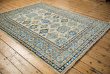 Angled view of a Pakistani Kazak rug's blue geometric medallions and intricate borders.