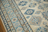 A close view of the Kazak rug's plush pile, showing its striped border and blue geometric medallions.