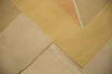 Hand-woven Kilim carpet corner, showing gold, beige, terracotta argyle diamonds and intact selvage.
