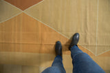Contemporary hand-woven Kilim rug featuring argyle diamond pattern in soft ivory, beige, and copper.