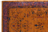 Close-up of the vintage carpet's corner, with cobalt blue scrolls on a purple floral border.