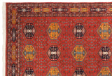 Corner of terra cotta rust vintage Pakistani Caucasian rug, detailed geometric blossomed patterns, and intact selvage.