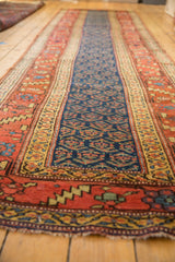 Antique Kurdish runner's end, highlighting the wide banded terra cotta borders and navy boteh pattern.