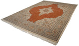 Angled view of a vintage Tabriz carpet highlighting the terracotta field and intricate floral borders.