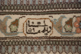 Finely knotted signature cartouche in brown and ivory on a handwoven Persian Tabriz carpet.