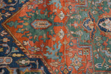 Detailed view of the Indian Heriz rug's terra cotta, emerald, and blue geometric vinery.