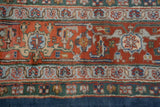 Vintage Indian Heriz carpet detail: terra cotta field with intricate vinery and patterned borders in emerald and denim blue.