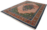 Hand-knotted Indian Serapi rug corner with abrashed blush field, green spandrel, and rust border.