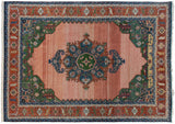 Corner of vintage Serapi rug, displaying geometric motifs in green, rust, and denim blue.