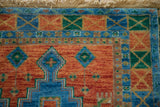 Vibrant terra cotta, sapphire blue, green checkered lily motifs on Indian Caucasian rug corner.