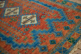 Vibrant terra cotta field, sapphire blue serrated borders, and intricate plant motifs.