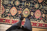 Vintage Indian Serapi Soumac rug's black field, red border, and detailed palmettes with a foot.