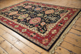 Corner view of Indian Serapi Soumac carpet, black field with palmettes, wine red border, beige fringe.