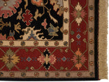 Serapi Soumac rug corner with red geometric border, ivory band, black floral field, and fringe.