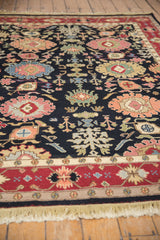 Colorful palmettes and vines on dark vintage Serapi Soumac field with bold red border.
