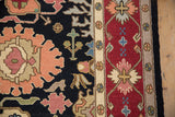 Hand woven Indian Serapi Soumac rug detail: black field with floral palmettes, wine red border.