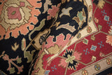 Textured hand-knotted pile of Indian carpet with black, wine red, and peach floral details.