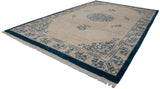 Corner of vintage Indian Peking rug, indigo blue border, germinating plants, and fringe.