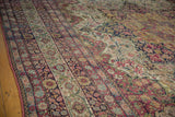 Angled view of an antique Kermanshah carpet highlighting its intricate floral border and low pile.