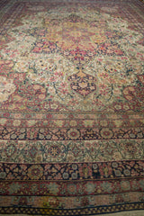 Angled view of an antique Persian Kermanshah showing its time-softened pile and sprawling floral vinery.
