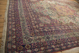Corner perspective of an antique Kermanshah carpet showing its detailed floral borders and ivory fringe.