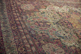 Time-softened low pile revealing hand-knotted florals of an antique Kermanshah carpet.