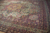 Storied patina and intricate floral design of an antique Kermanshah carpet seen from a low angle.