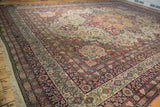 Complex floral borders in navy blue, cochineal red, and ivory on an antique Persian Kermanshah carpet.